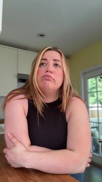 woman sighs, shrugs shoulder, and rolls eyes in frustration