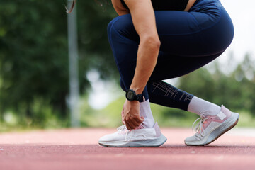 Obraz premium Woman Tying Shoe Laces During Outdoor Workout Session on a Track