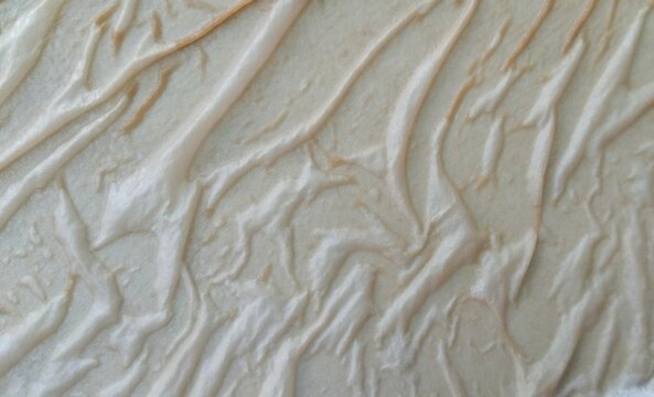 Abstract embossed wallpaper texture with light beige wavy pattern close up