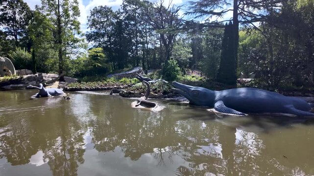Historic Crystal Palace Dinosaurs sculptures in a pond with ducks swimming by in a London park
