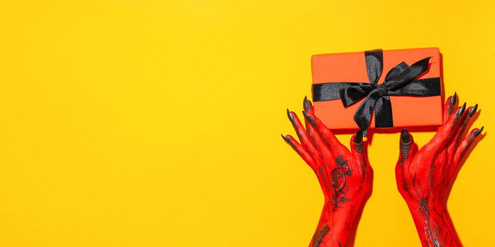 Halloween. Hands painted red present a spooky Halloween gift box