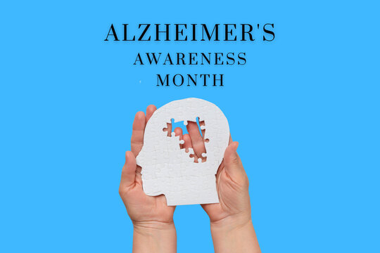 Hands hold a puzzle piece representing Alzheimer's awareness