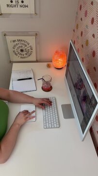 overhead angle of person typing on a dekstop computer with a salt lamp and journal nearby