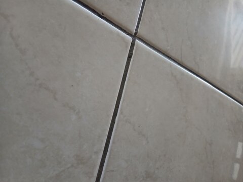 Close up shot of grey ceramic floor tiles with dark grout seam lines creating a clean minimalist texture
