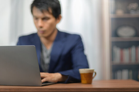 Business Professional Working on Laptop at Desk with Coffee in Modern Office