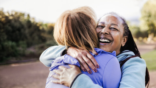Multiracial senior women hugging each other in public park - Elderly friendship and love concept