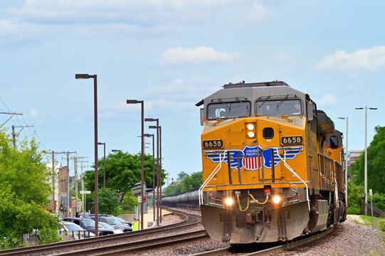 With the train spread out behind, a pair of Union Pacific Railroad locomotives lead an empty ethanol train into a curve while passing westbound through the Chicago suburbs.