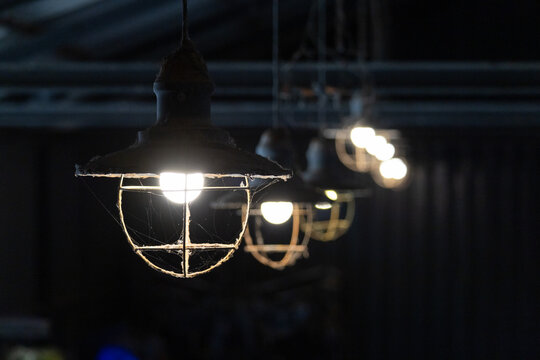 String of vintage cage lights illuminating dark industrial space