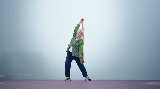 Senior Asian woman practicing tai chi in foggy outdoor nature during morning routine, active senior lifestyle and wellness concept
