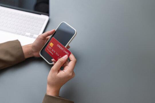 Businesswoman holding a red credit card and smartphone for secure mobile payment and online banking with copy space.