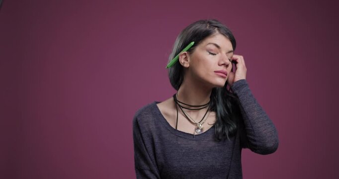 Contemplative woman holding a pen against a purple background