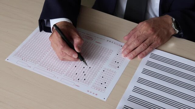 マークシート方式の解答用紙にペンで回答を記入する手元