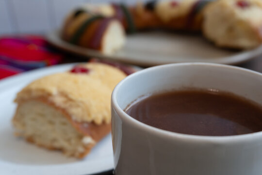 Cup chocolate, a slice of "Rosca de Reyes" on a table in the background