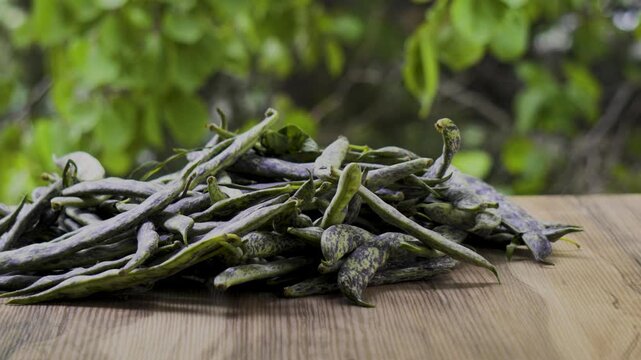 Green beans on wooden table with leaves background taken by hand, 4K