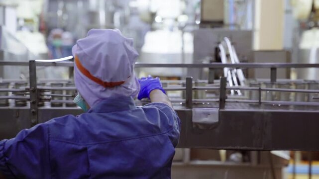 Quality control worker inspecting metal cans on conveyor belt