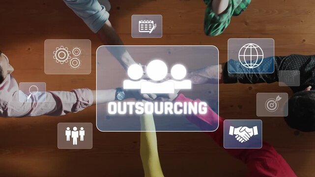 This image depicts a collaborative outsourcing concept featuring hands and various business icons on a wooden table, symbolizing teamwork and global connections. Raster