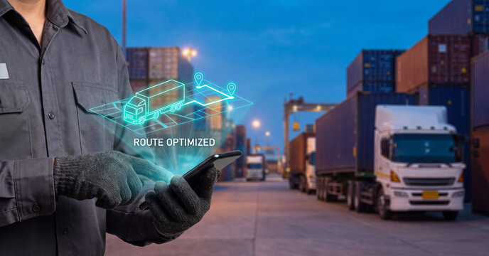 Logistics manager using smartphone to track digital truck route optimization software at a busy industrial shipping container freight yard port