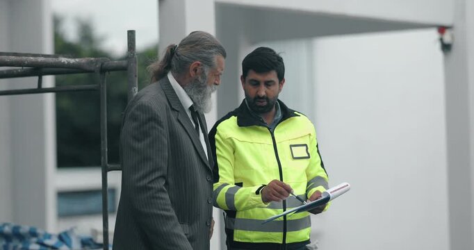 Engineer and businessman inspecting house construction site while discussing building project