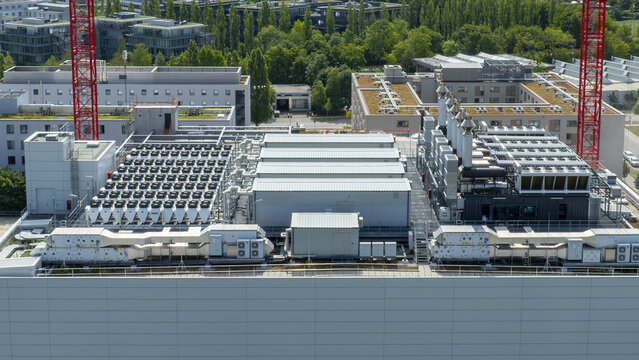 Aerial view of the industrial rooftop featuring extensive HVAC cooling systems and ventilation units with construction cranes in the background in Munich, Bavaria, Germany.