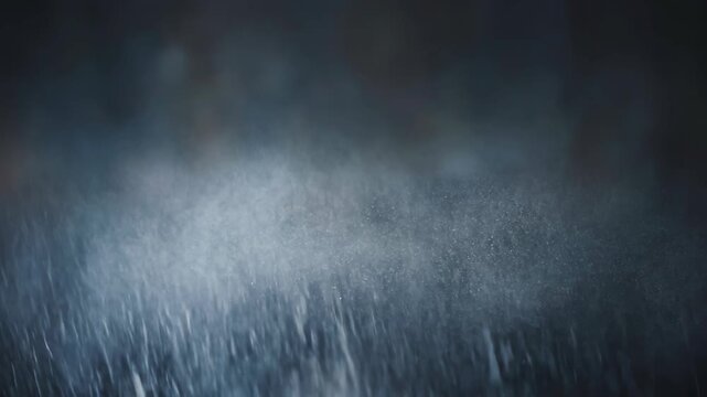 Rain falling on dark surface creating misty atmosphere for dramatic effect