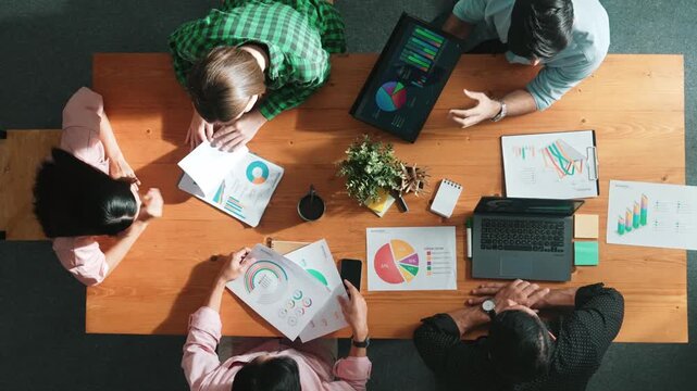 Top view of project manager using tablet to analyze data and financial chart while marketing team working together to brainstorm marketing campaign or planning strategy at meeting room. Convocation.