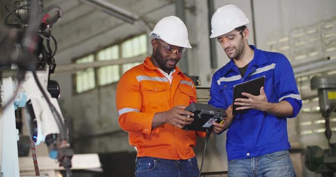 Professional industrial engineer African american man holding automation robot arms machine controller talking to his Chief in smart manufacturing industry. Technology and Innovation concept.