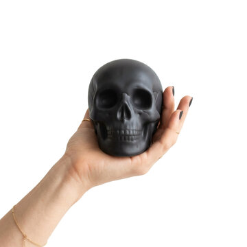 Hand holding a matte black human skull. Dark aesthetic and mortality concept