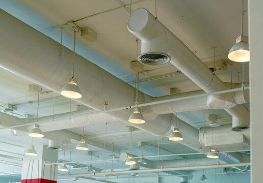Air duct, wiring and plumbing in the mall. Air conditioner pipe, wiring pipe, and plumbing pipe system. Ceiling lamp light with opened light. Building interior concept. Interior architecture concept.