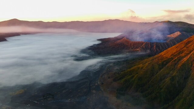 Aerial view of Mount Bromo with volcanic crater and sea of clouds at sunrise in Tosari, East Java, Indonesia.