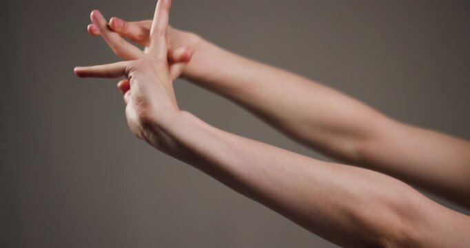 Close-up of interlocked hands showing gestures and body language on a neutral background