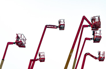 Collection of hydraulic articulated boom lifts raised into working position with large copy space. Aerial work platform rental, construction industry, engineering and industrial maintenance. © Fahroni