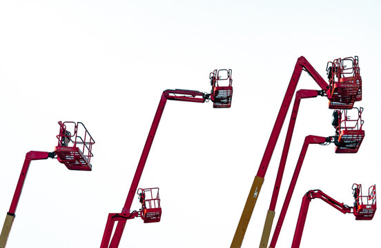 Collection of hydraulic articulated boom lifts raised into working position with large copy space. Aerial work platform rental, construction industry, engineering and industrial maintenance.