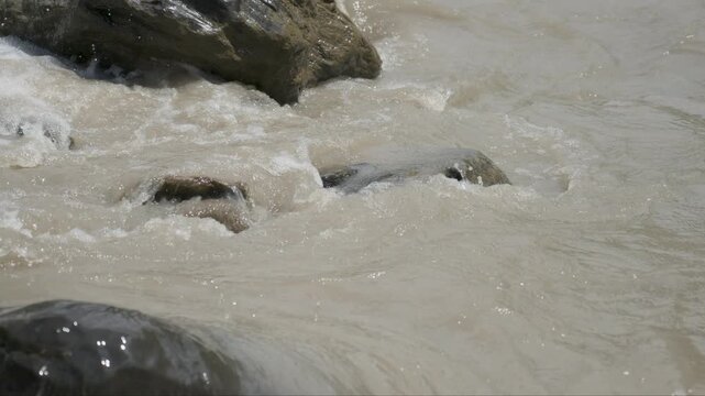 Close Up Muddy River Water Swirling and Flowing Around Submerged Rock 4K