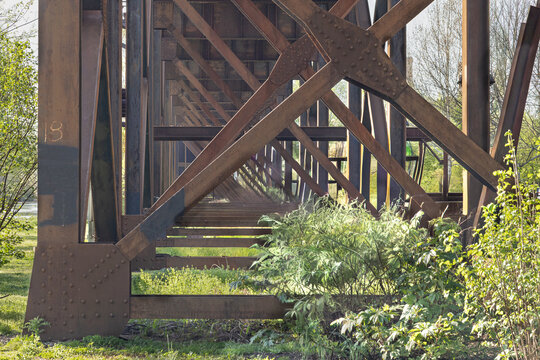 Geometric oxidized iron beams and rivets supporting a train trestle in historic Shockoe Bottom, Richmond, Virginia.