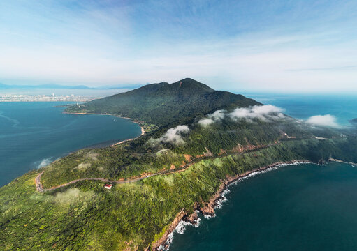 An aerial view shows the Son Tra Peninsula in Da Nang, Vietnam, with its densely forested mountain slopes meeting the clear blue ocean and a sandy beach