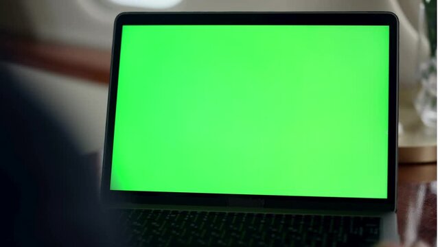Close up of laptop with green screen chroma key mockup in airplane cabin