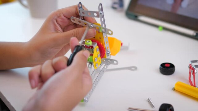 Close up of child hands assembling 3D printed robot model on table. Concept of STEM education, robotics learning, creativity, and technology development