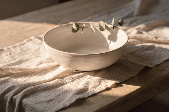 Ceramic Bowl with Eucalyptus Branch on Rustic Linen and Wood