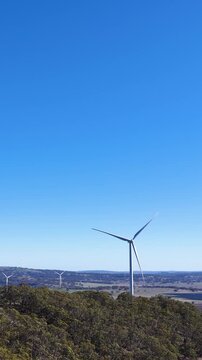 Wind Turbine Spinning in Rural Landscape Under Clear Blue Sky