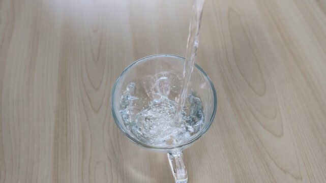 Fresh Water Pouring into Clear Glass Cup on Wooden Table