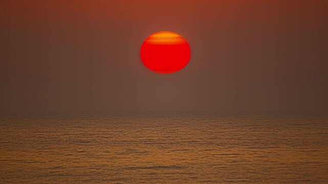 View of a vibrant red sunset over the calm waters of the Baltic Sea in Riga, Latvia.