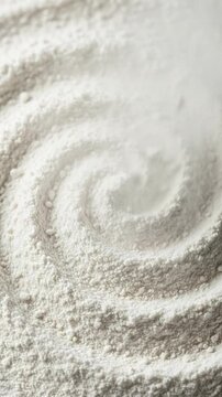 A top-down close-up view of white wheat flour arranged in a decorative spiral pattern texture.