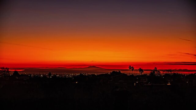 View of the San Francisco skyline silhouetted against a vibrant orange and red sunset sky over the hills of California, San Francisco, California, United States.