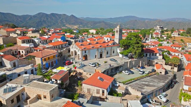Aerial view of Pano Lefkara village in Cyprus. Traditional red roofs, hillside homes and surrounding mountains create a peaceful Mediterranean village scene.