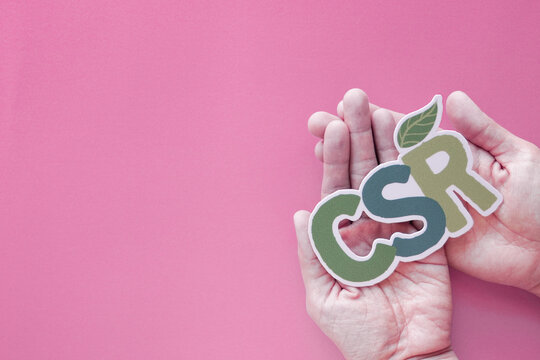 csr, corporate social responsibility, sustainability, esg, ecology, environment, business ethics concept shown with hands holding paper sign over pink background with copy space.