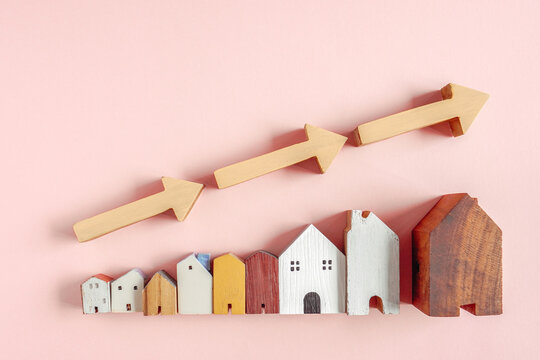 Real estate, Housing market, Growth, Investment, Property, Mortgage, House prices rising shown with yellow arrows and miniature wooden buildings over a pink background for business.