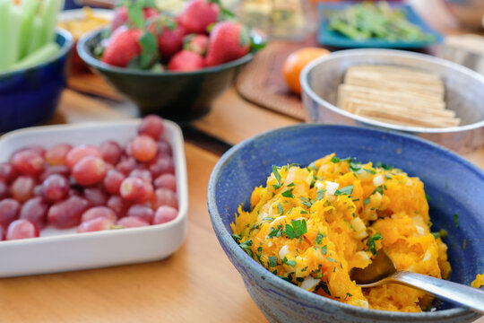 Healthy food, appetizer spread, mashed squash, plant based, fruit platter, vegan snack, party food featuring strawberries and grapes served on a rustic table at a sunny brunch.