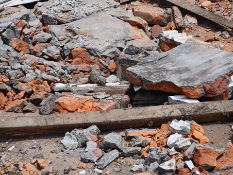 Debris of broken red bricks and grey concrete slabs on construction site