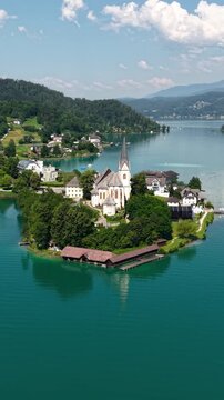 Vertical Drone Shot of Catholic Church in Maria Worth, Austria. Village Landmark by Worthersee Lake on Sunny Summer Day