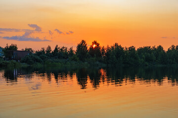 Naklejka premium Golden orange sunset over Big Chebachye lake. Vivid gradient sky and ripples on calm water. Scenic background with symmetry reflection evening sky. Burabay National Nature Park Travel destination.